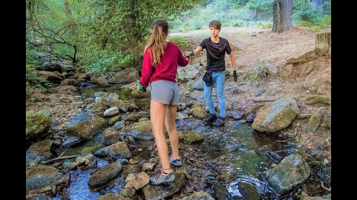 Jóvenes cruzando un río por las piedras