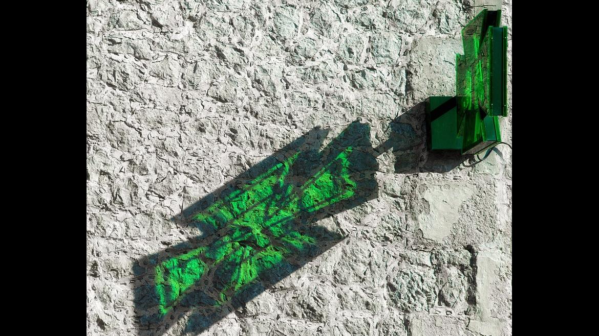 Cruz verde reflejado en pared