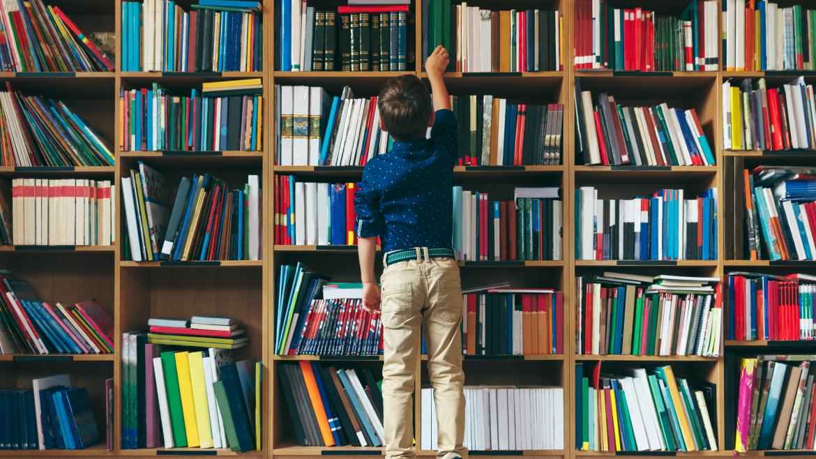 Niños seleccionando un libro en una biblioteca