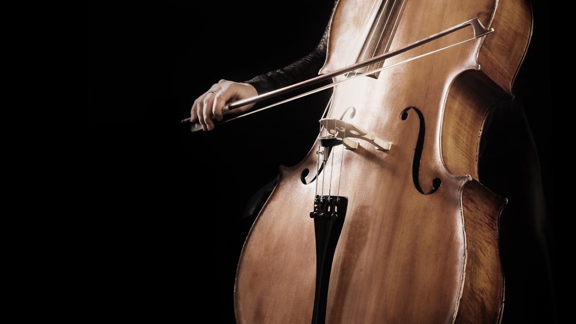 Persona tocando el violonchelo sobre un fondo negro
