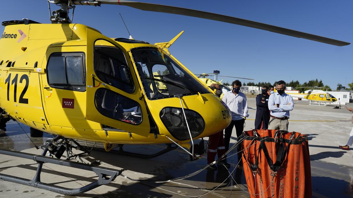 Carlos Novillo visita la helisuperficie de la Dirección General de Emergencias en Las Rozas de Madrid El viceconsejero mirando un helicóptero en tierra y la bolsa que suelen utilizar para la recogida de agua