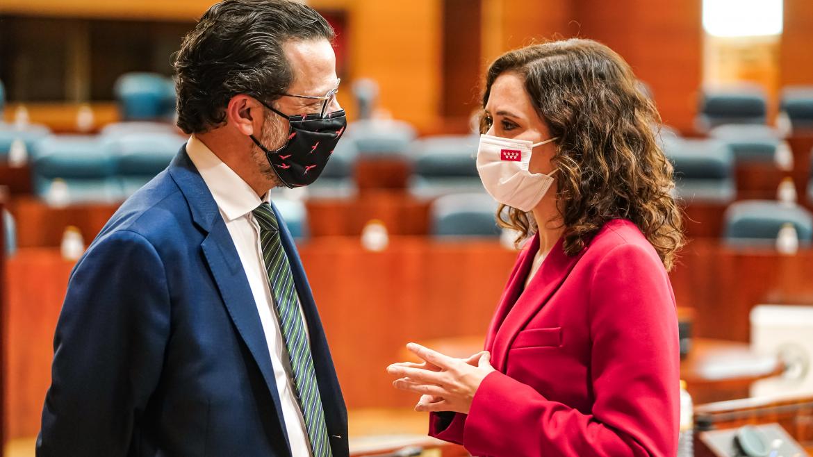 El consejero Javier Férnandez-Lasquetty hablando con la presidenta en la Asamblea de Madrid