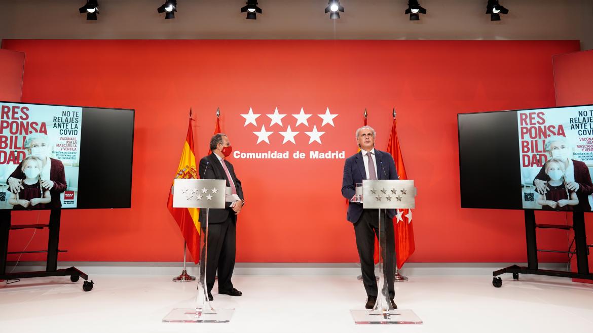 Los consejeros interviniendo en el atril con una de las imágenes oficiales de la campaña en las pantallas a su lado izquierdo y derecho