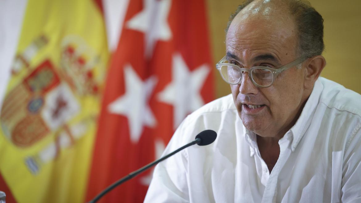 Primer plano del director general de sanidad con las banderas de la Comunidad de Madrid y España de fondo