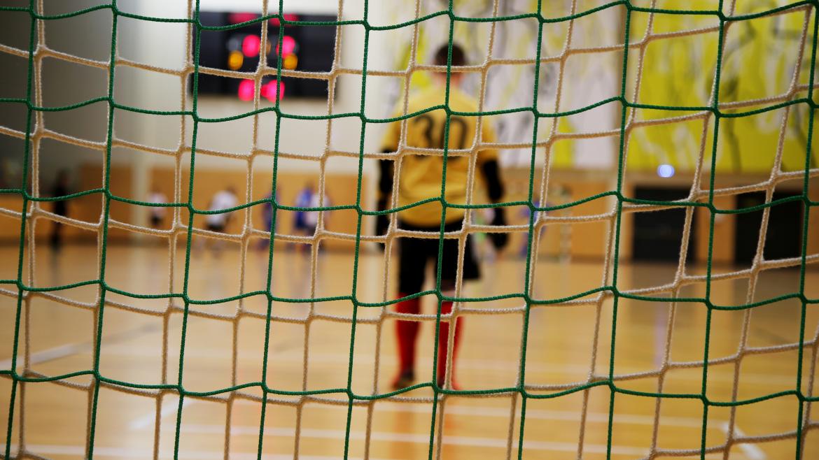 Portero de fútbol sala Un portero de fútbol sala de espaldas visto a través de las redes de la portería