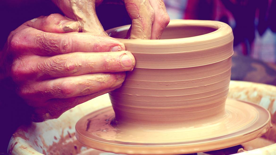 La mano de un artesano moldeando un jarro de cerámica