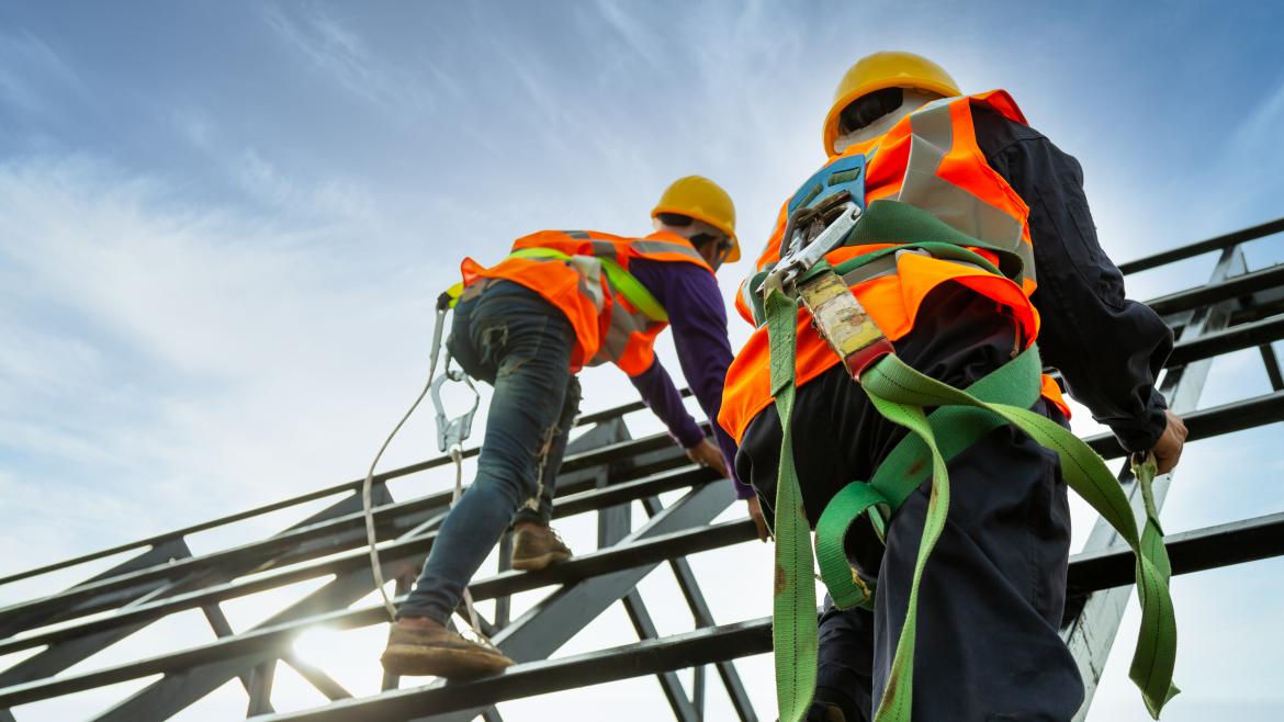 Dos trabajadores con su correspondiente equipo de protección subidos a un andamio