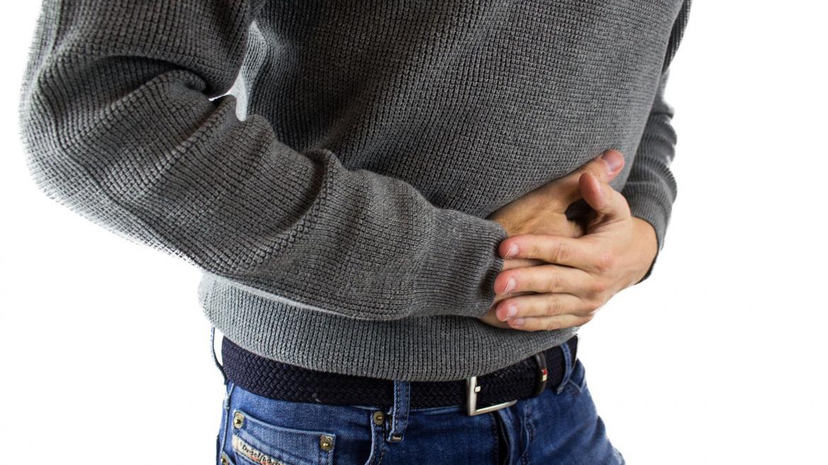 Un hombre manifiesta dolor y pone sus manos en el estómago