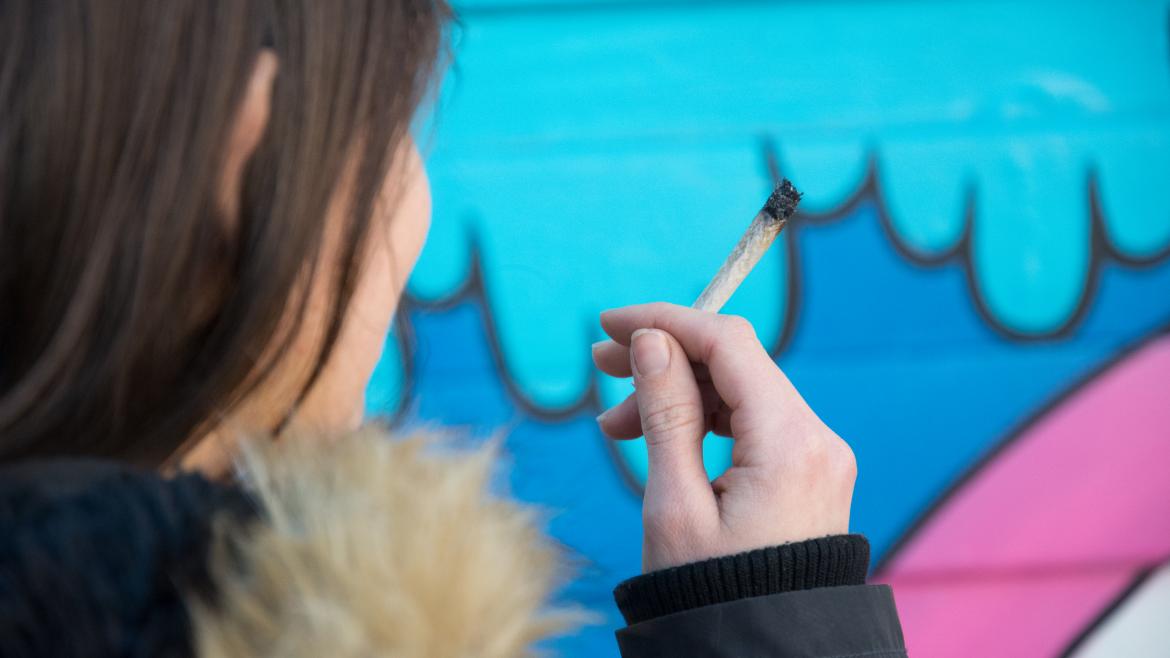 Una joven sostiene un cigarro de cannabis