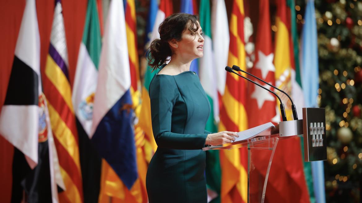 La presidenta con un vestido verde delante de las banderas en el acto