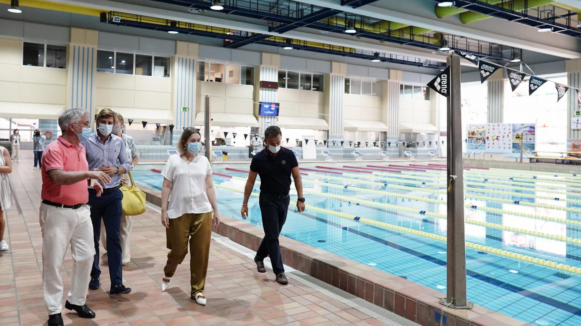 Marta Rivera visita el Centro de Natación Mundial 86 La consejera caminando al lado de una piscina mientras escucha la explicación de unos de los responsables de las instalaciones