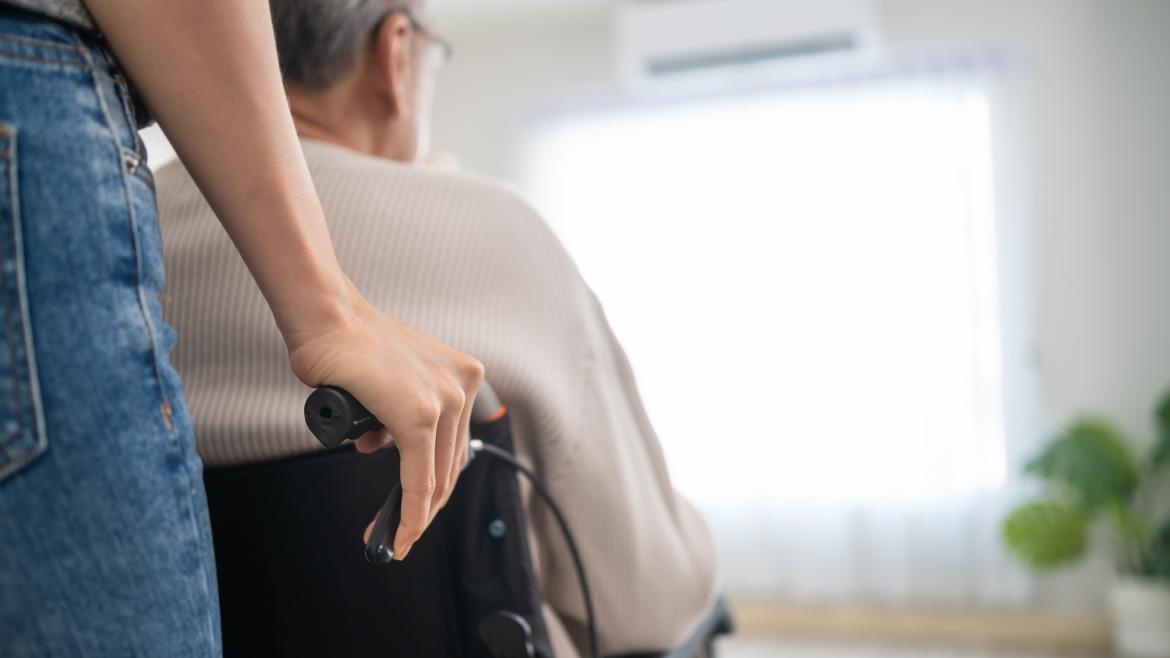 Una enfermera empuja una silla de ruedas con un señor sentado en ella
