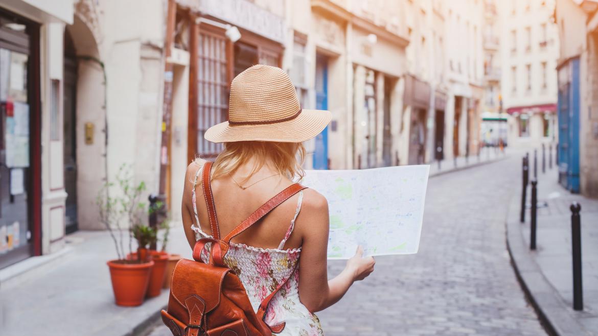 Francesa, mayor de 40 años y con interés por la cultura: perfil de los turistas que llegan a la Comunidad Una turista de espaldas con un mapa