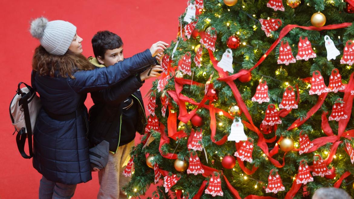 La Comunidad de Madrid incrementó un 25% el número de visitantes durante la Navidad en Sol Una madre y un hijo colocando sus deseos en un abeto