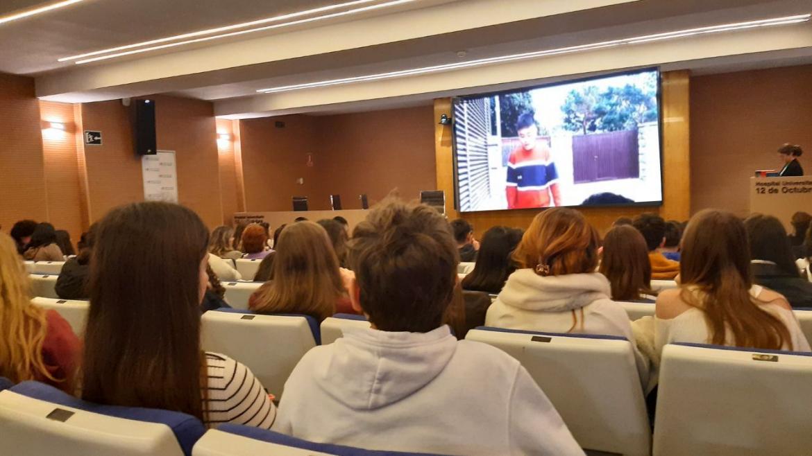 salón de actos con gente visto desde el centro y con imagen en pantalla