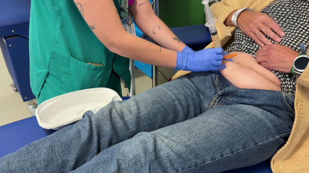 Administración del tratamiento del ensayo clínico MajesTEC-e a una paciente Enfermera pinchando un tratamiento a una paciente sentada