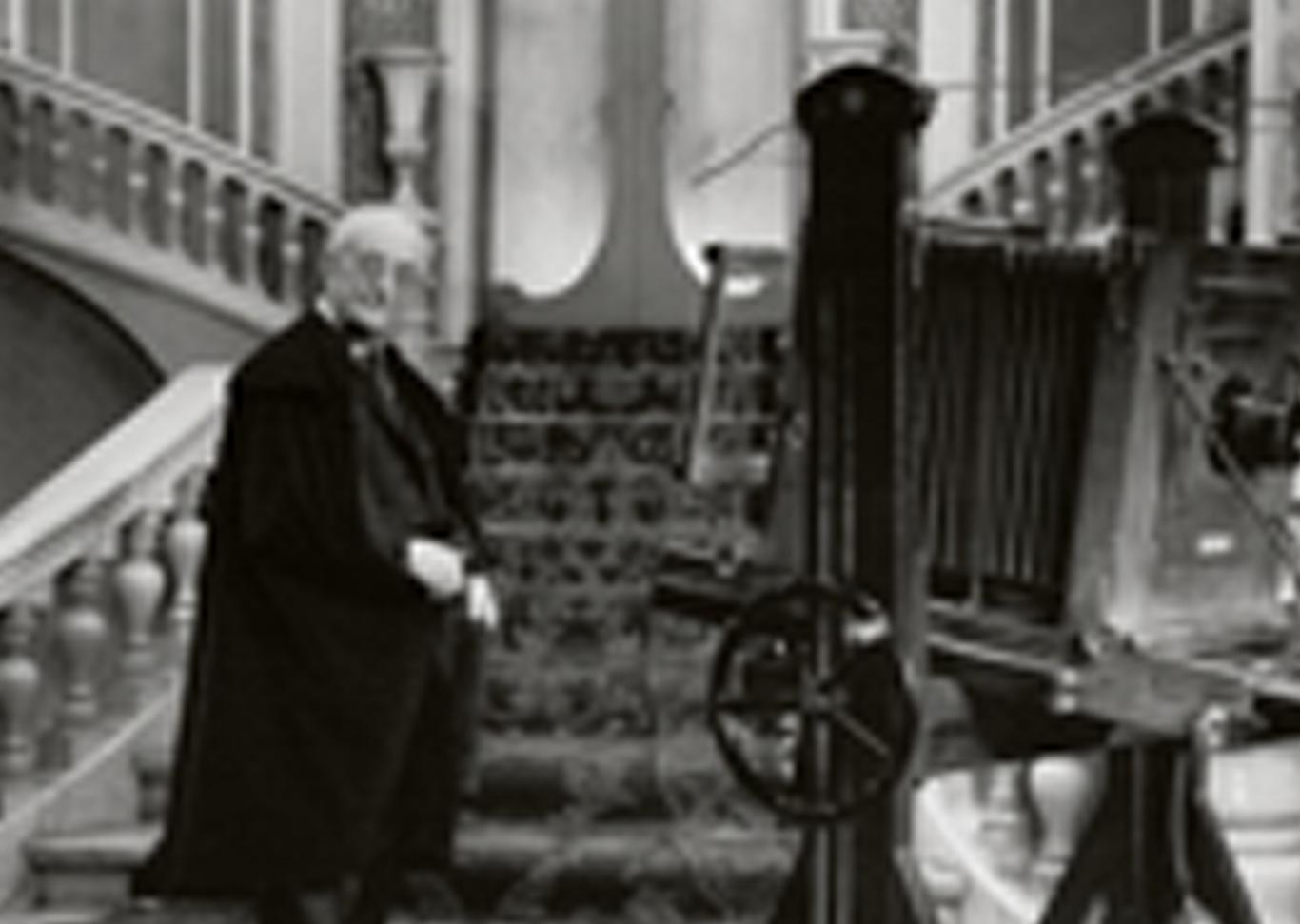 Hombre vestido con capa española posa con cámara fotográfica antigua