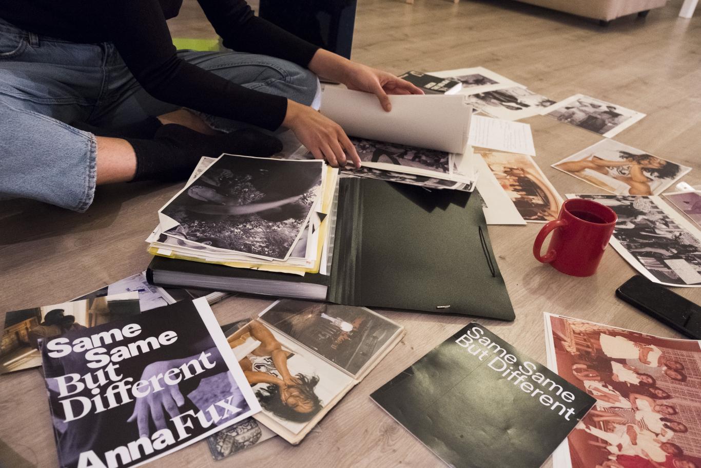 Persona sentada en el suelo hojeando libros y revistas