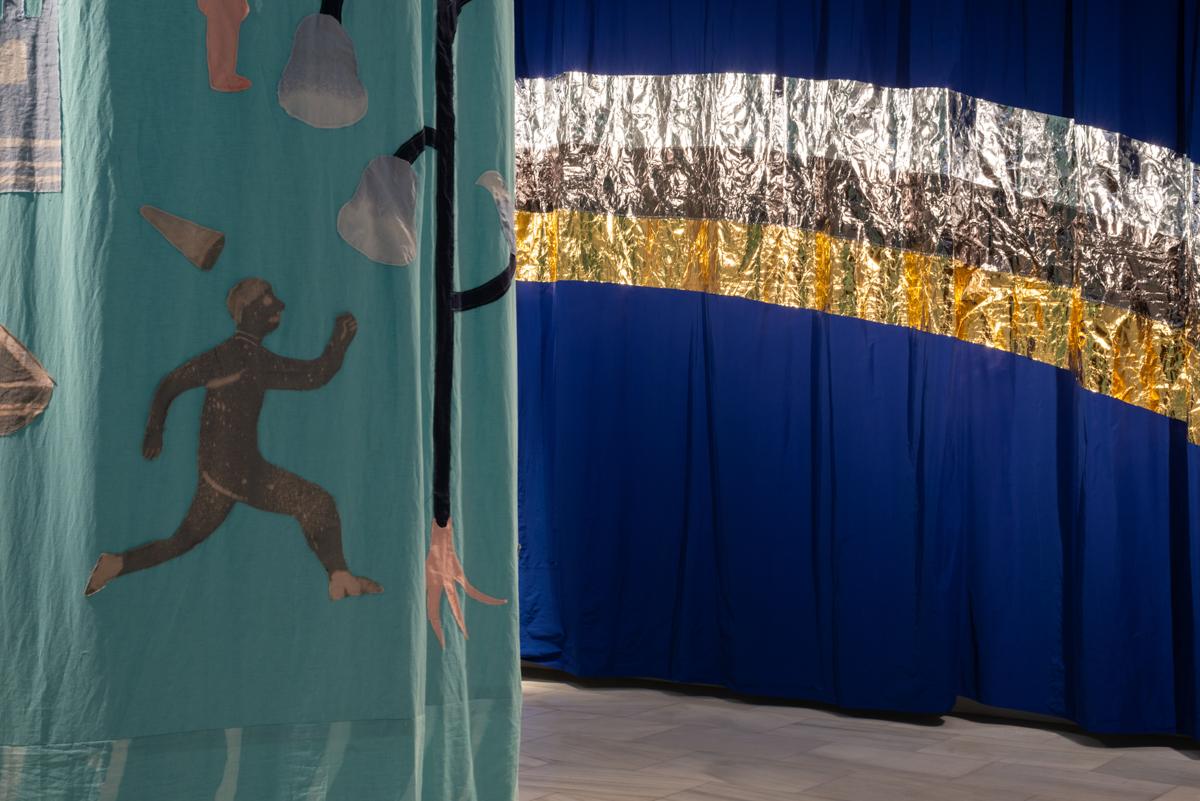 Cortina azul con arco iris dorado y tapiz con figuras de lobos y personas con capirote