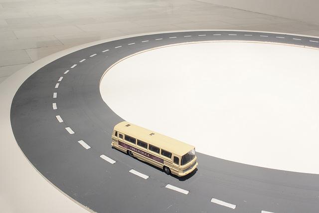 Instalación artística que simula una carretera y un autobús amarillo de juguete sobre ella