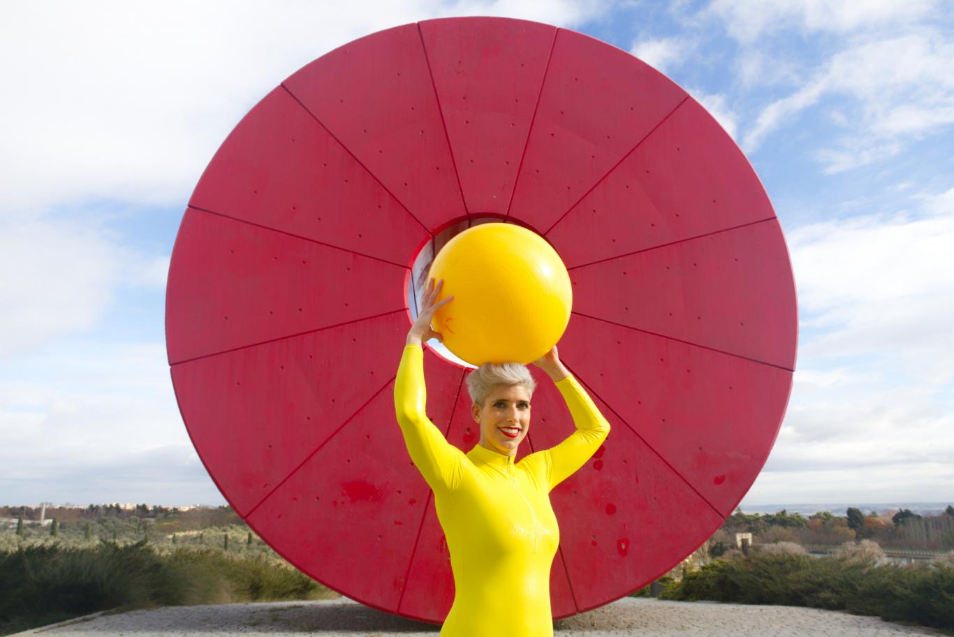 Mujer con maillon amarillo sujetando una pelota de yoga roja