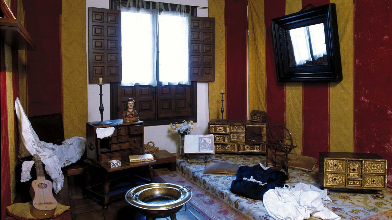 Habitación con tarima en el suelo, tapices, alfombras, brasero antiguo y piezas de hogar 