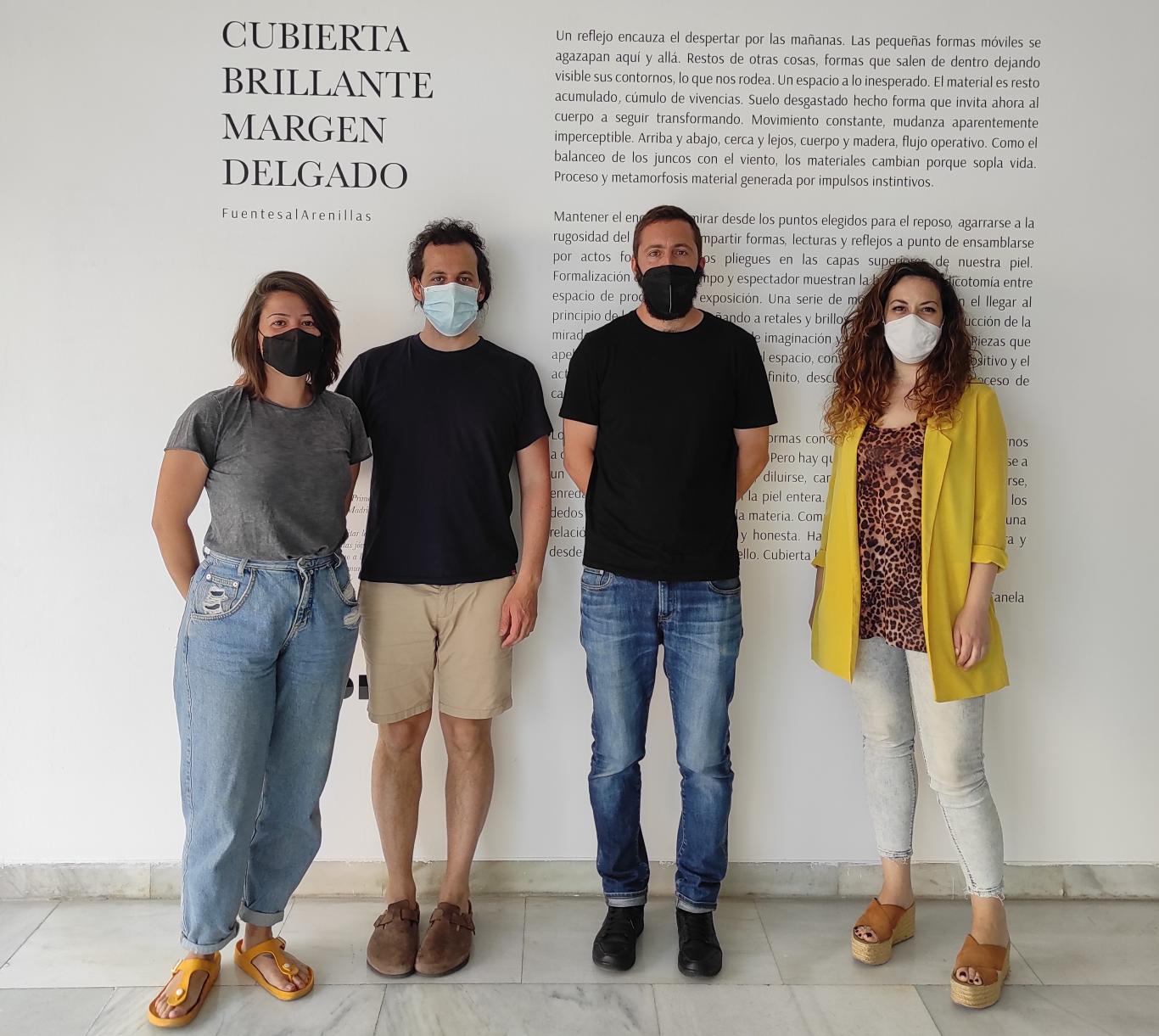 Retrato de cuatro personas frente al cartel de la exposición