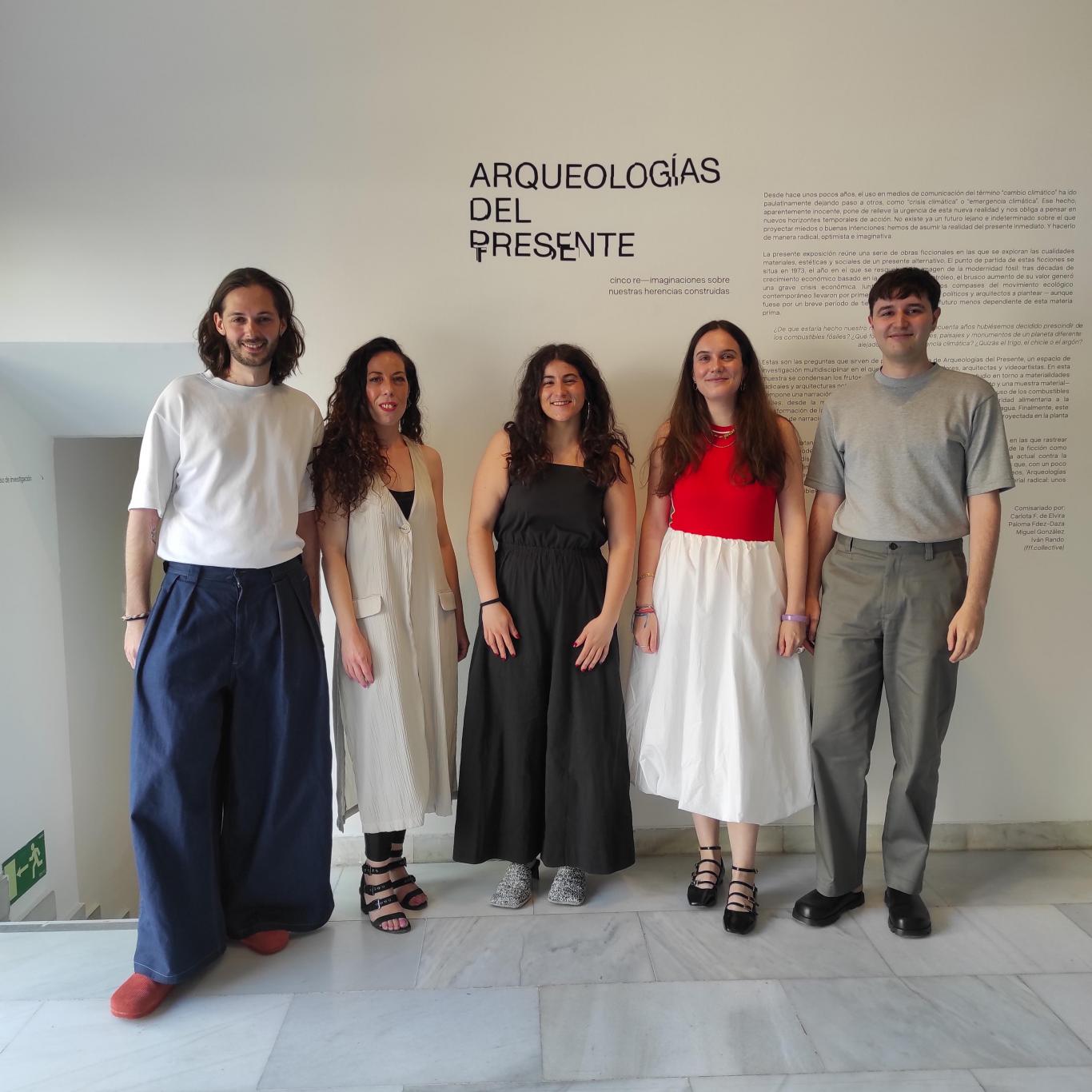 CInco jóvenes posando frente al título de una exposición donde se lee Arqueologías del presente
