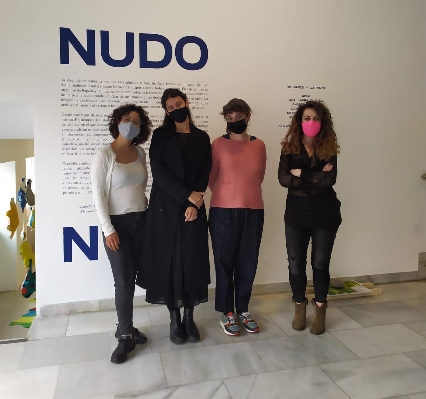 Artistas y comisarias posando delante del cartel que anuncia la exposición Nudo Nido