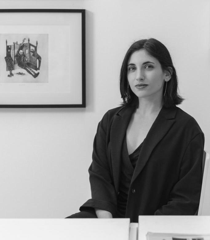 Imagen en blanco y negro con el retrato de una mujer joven, sentada y que mira a cámara