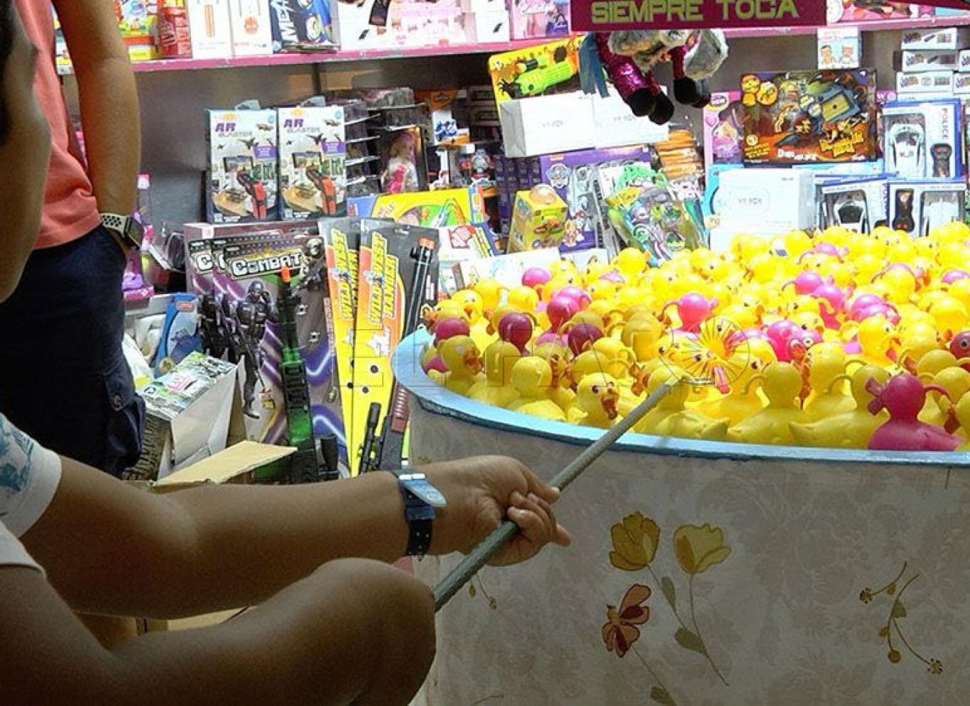 Niño en una feria intentado pescar patos de goma con una caña