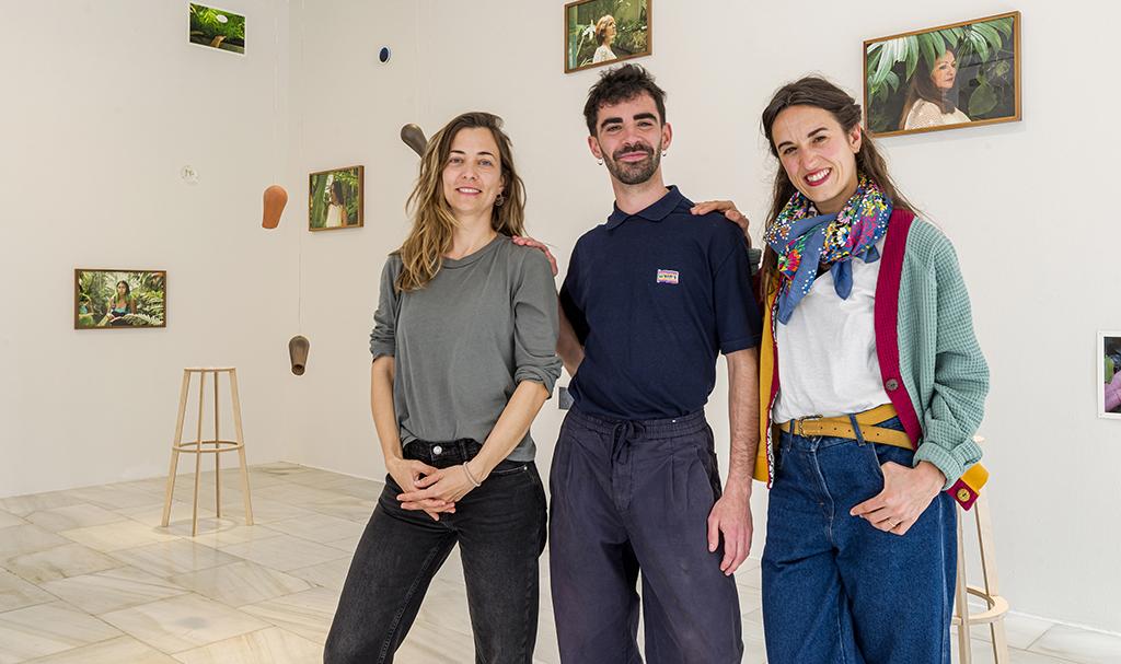 Tres jóvenes posan y miran a cámara en una sala de exposiciones