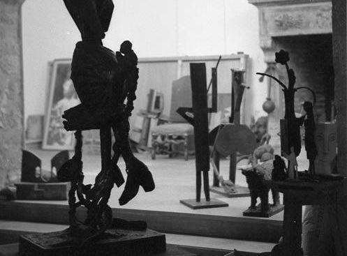 Vista de una sala que es el taller del artista lleno de esculturas y lienzos