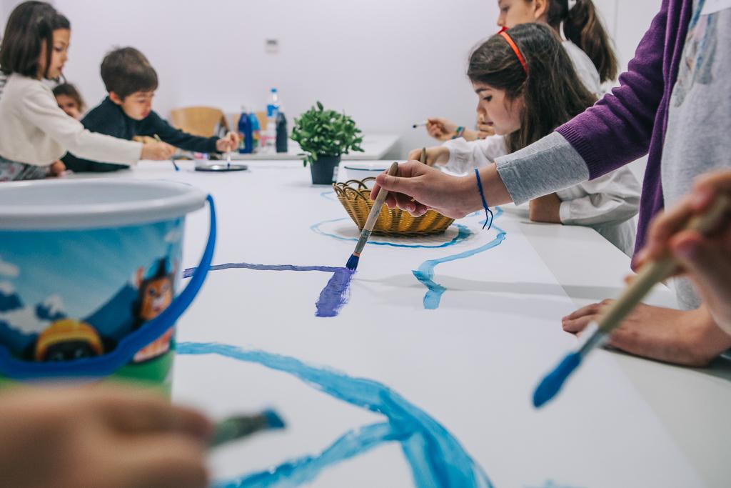 Grupo de niños dibujando un mural de colores sobre una mesa