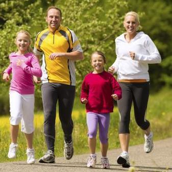 Dos padres y dos hijos corriendo por el parque