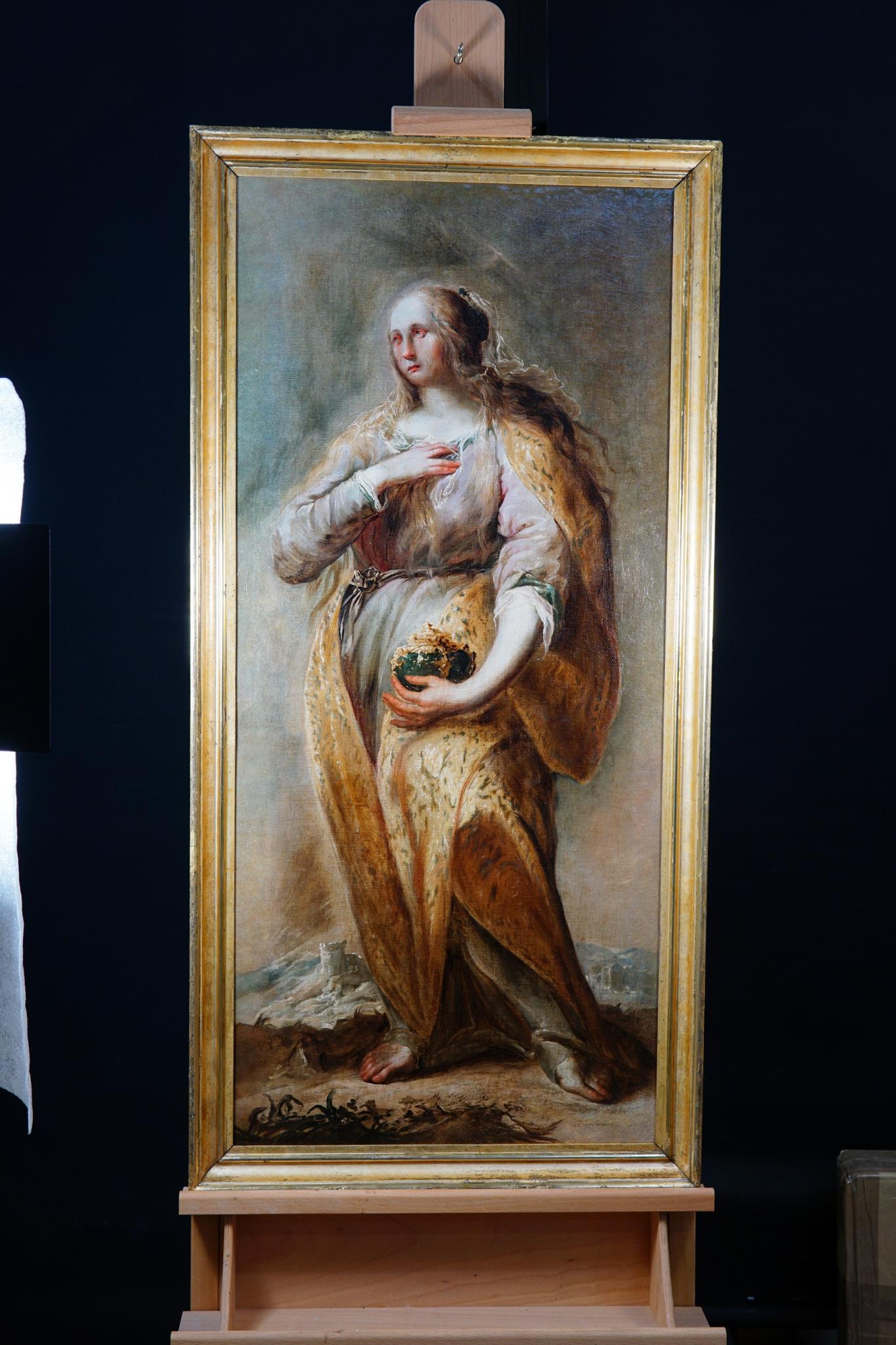 Retrato pictórico de una mujer de pie con el cabello largo y dorado, una mano en el pecho y la otra portando un frasco dorado