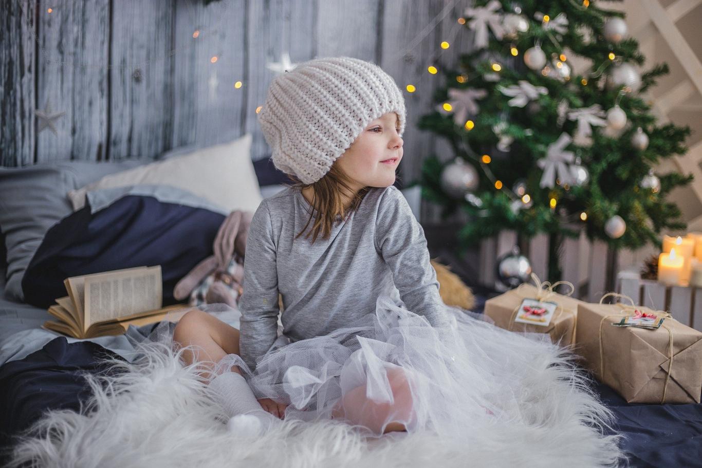 niña pequeña con árbol de Navidad y regalos