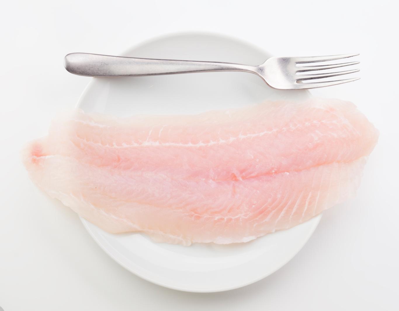 Filete de panga crudo en un plato con un tenedor