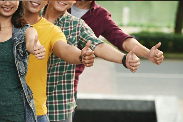 4 jóvenes con signos de dedo gordo en alto en la mano