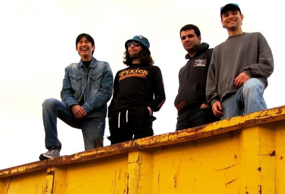4 jóvenes subidos a un contenedor amarillo sonriendo