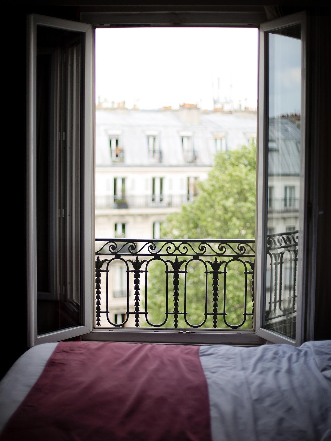 Imagen de la ventana abierta de un dormitorio en penumbra