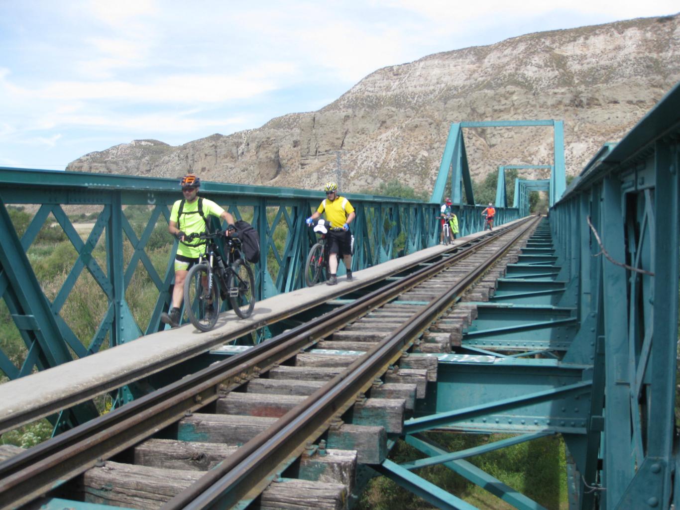 Ciclistas cruzando a pie el puente de hierro del antiguo tren de Arganda, sobre el río Jarama