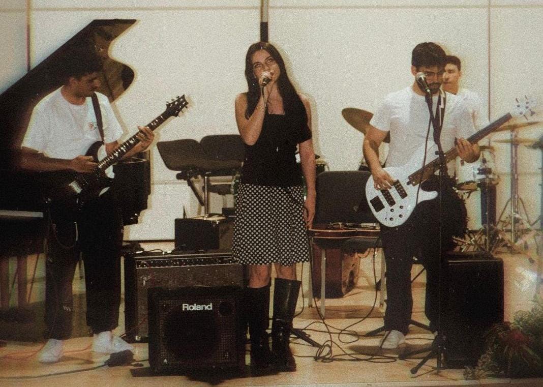4 jóvenes tocando y  cantando en el escenario