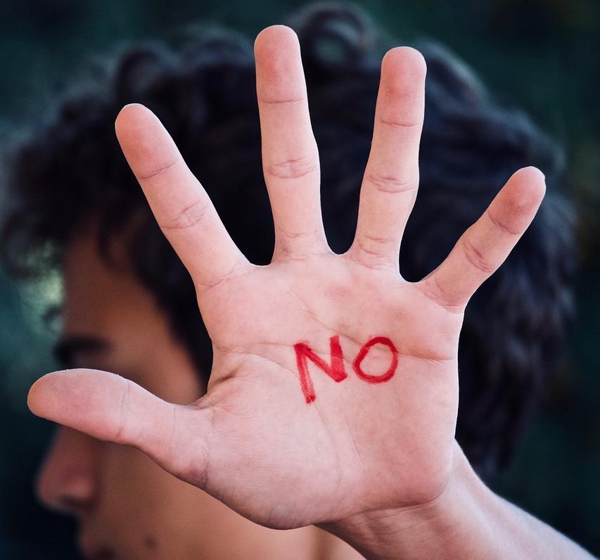 Joven levantando la palma de la mano con la palabra NO