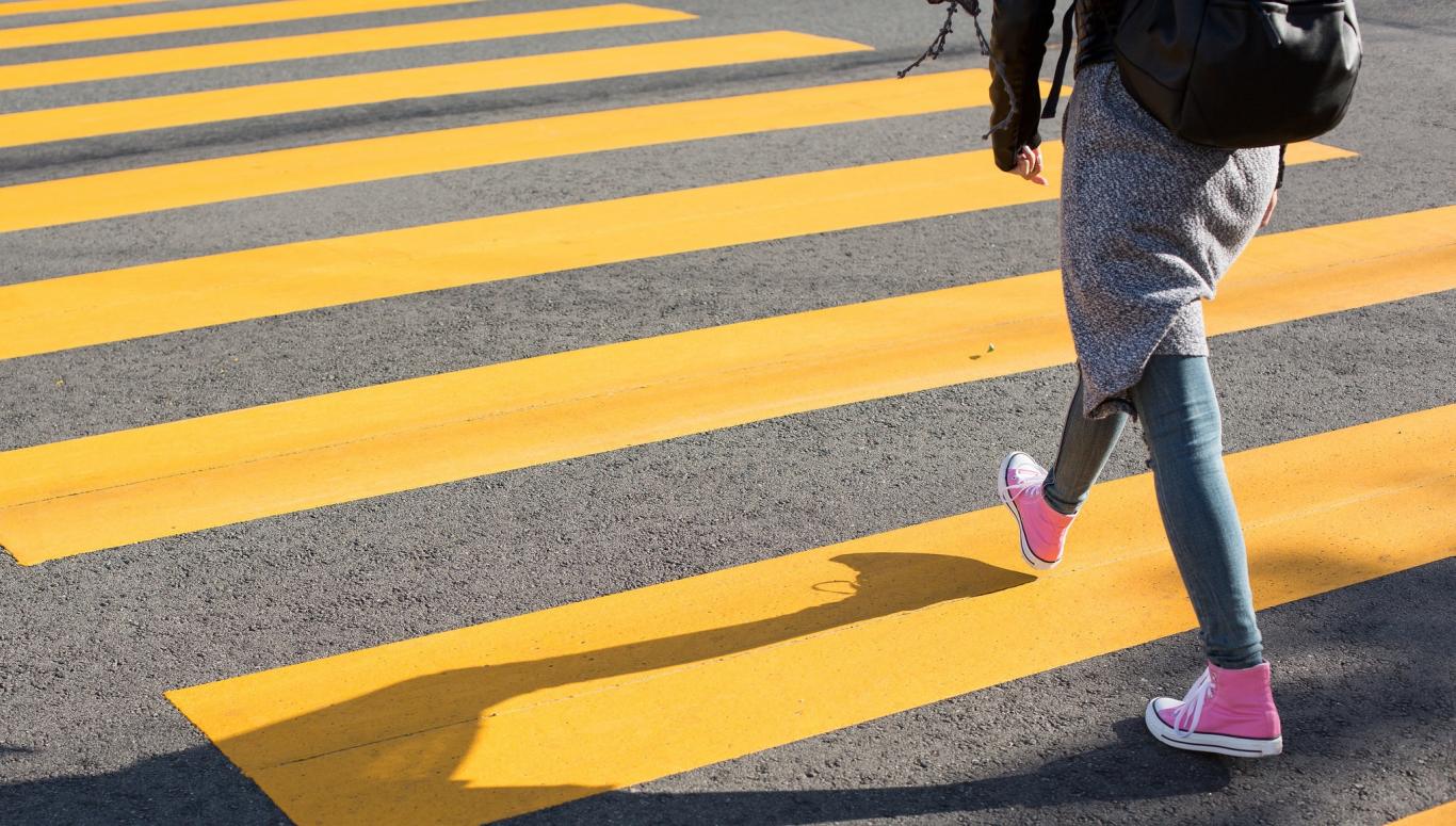 Joven cruzando un paso de cebra amarillo