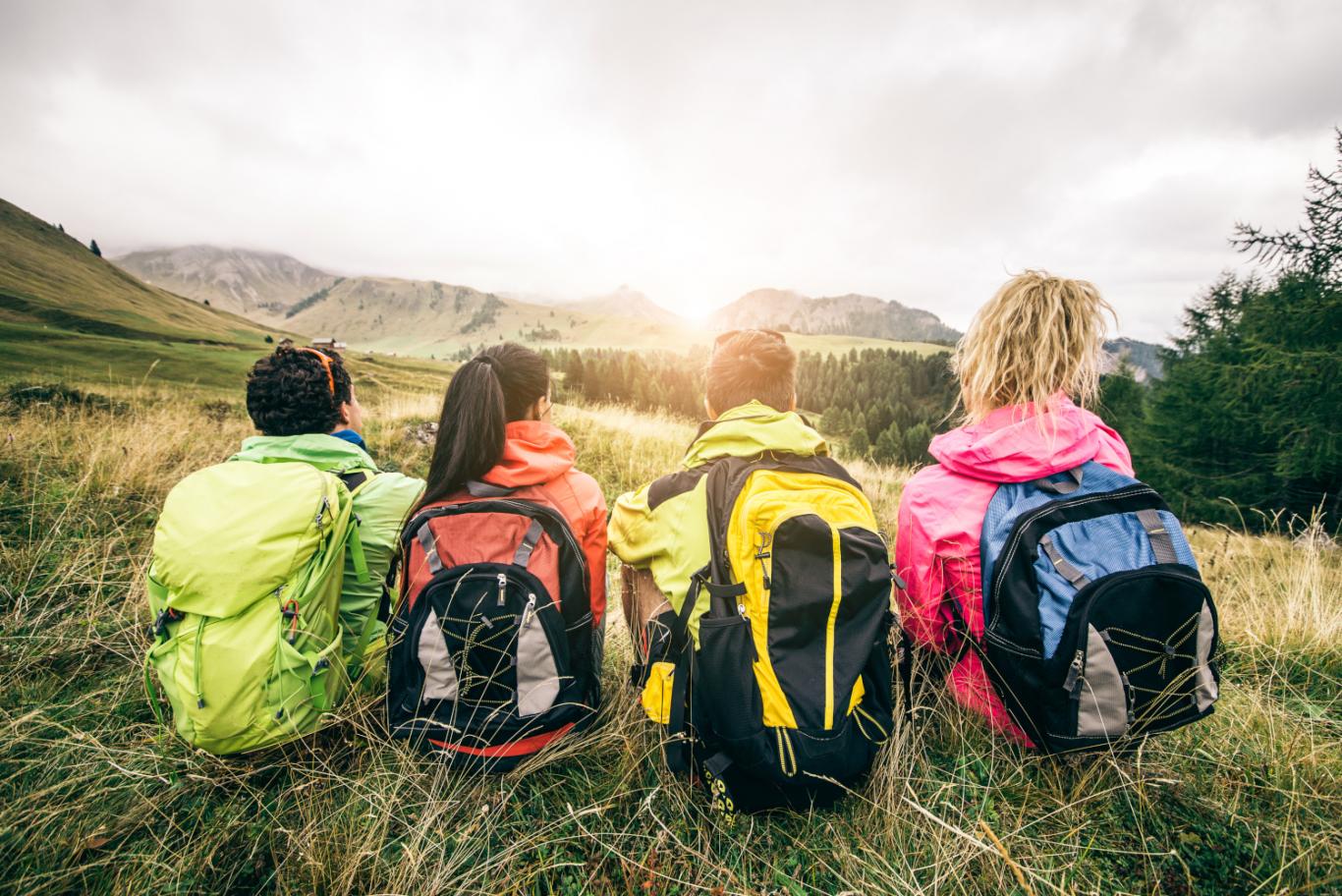 Jóvenes sentados de espaldas con mochilas