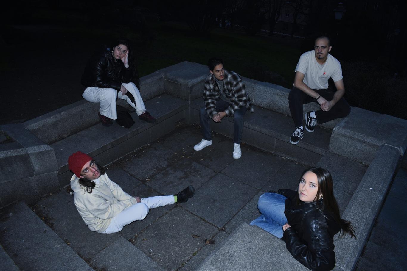 5 jóvenes sentados en monumento de piedra mirando para arriba