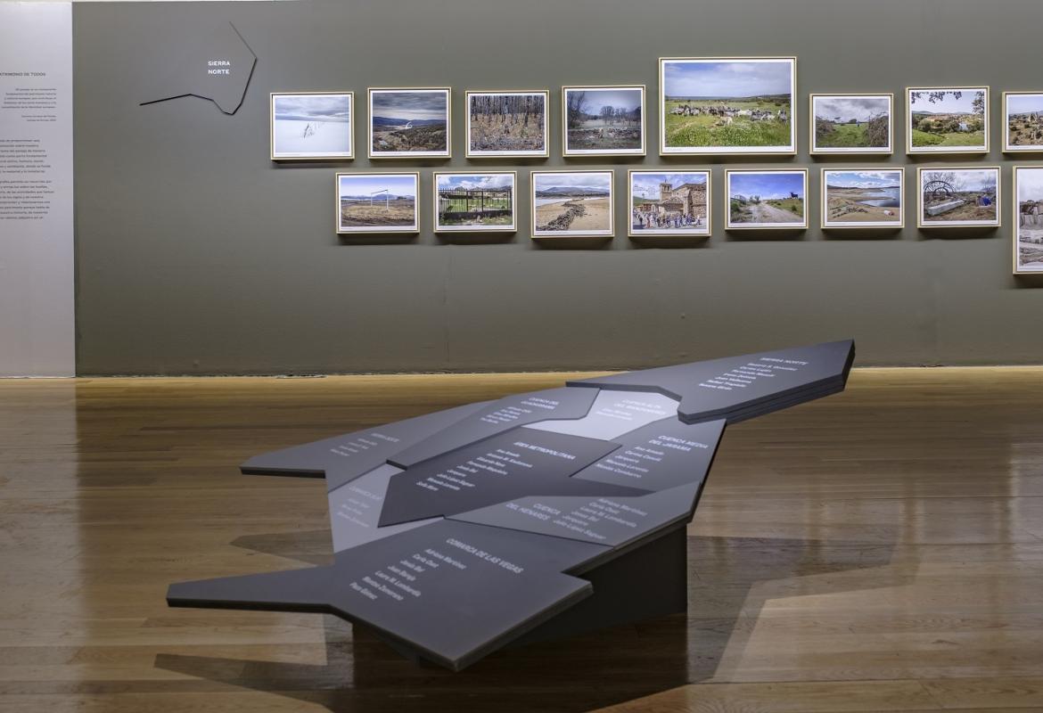 Vista de la exposición REGIÓN, Paisaje, fotografía y patrimonio, una maqueta con el nombre de los municipios y varias fotografías expuestas