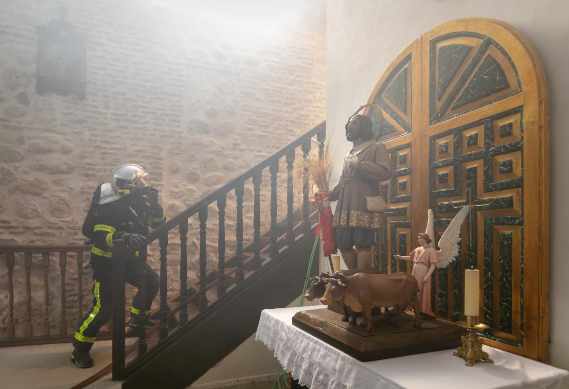 Bombero subiendo las escaleras en el interior de una iglesia, en primer plano una pieza