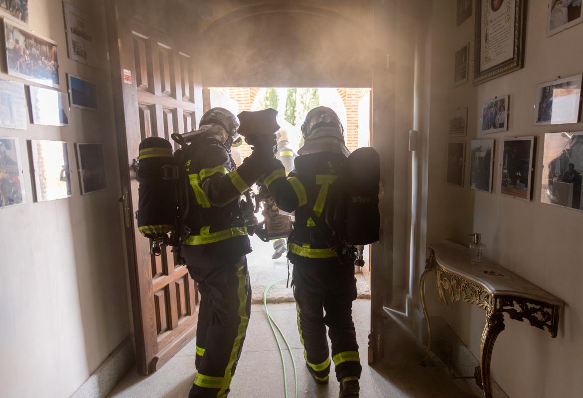 dos bomberos de espaldas trasladando una pieza fuera del museo